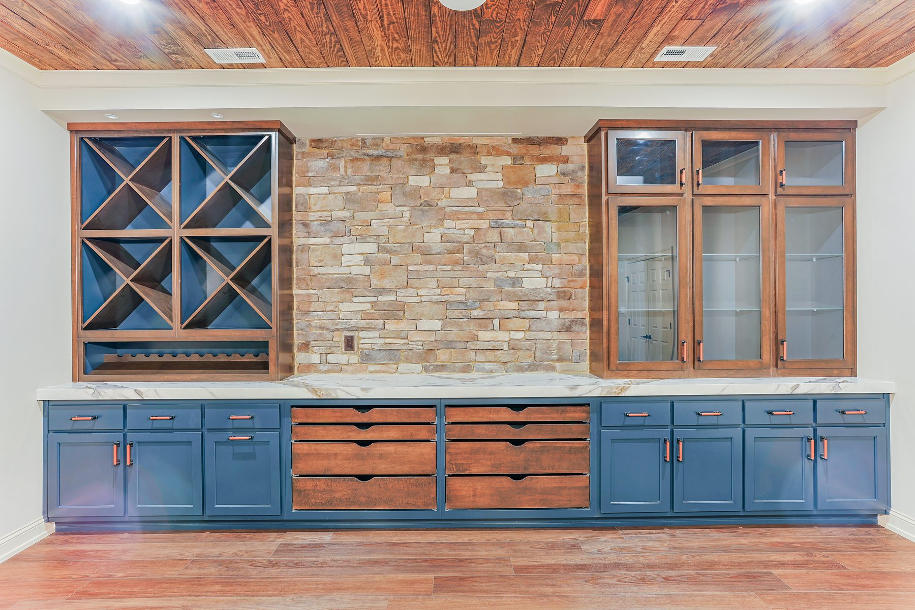 Custom blue and walnut wet bar with natural stone wall